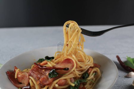 Espaguetis en un tenedor. Espaguetis Bacon ají albahaca al ají en plato blanco. Menú popular plato de cocina italiana clásica. Deliciosa comida picante.