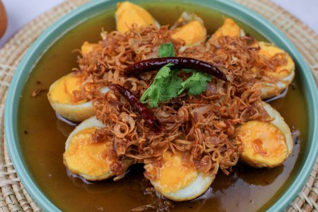 Gebratenes gekochtes Ei mit Tamarindensoße, garniert mit gebratenem Knoblauch, roten Zwiebeln und Koriander. Thailändische Küche. Selbstgemachtes.