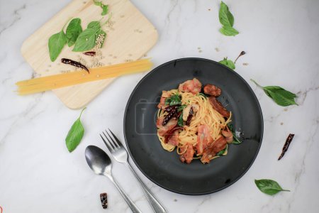Espaguetis con chile seco, albahaca y tocino sobre mesa blanca. Menú tradicional Popular plato de cocina italiana clásica. Deliciosa comida picante.
