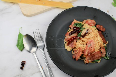 Espaguetis con chile seco, albahaca y tocino sobre mesa blanca. Menú tradicional Popular plato de cocina italiana clásica. Deliciosa comida picante.