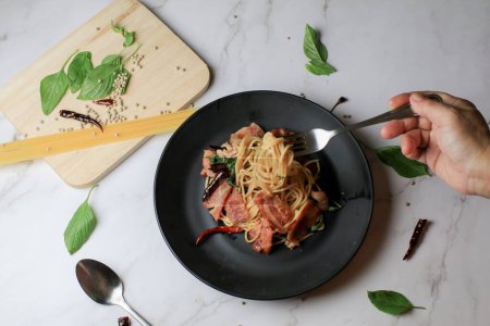 Espaguetis en tenedor con chile seco y tocino sobre mesa blanca. Menú tradicional Popular plato de cocina italiana clásica. Deliciosa comida picante.