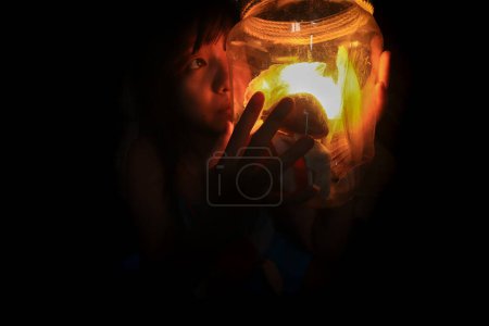 Téléchargez les photos : Jeune femme avec une bougie dans la nuit - en image libre de droit