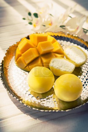 Leckeres Dessert Mochi mit Mangofrüchten auf hölzernem Hintergrund, aus nächster Nähe. Traditionelles japanisches Reiskuchendessert