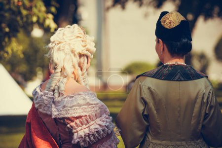 Portrait of two woman dressed in historical Baroque clothes with old fashion hairstyle, outdoors. Luxurious medieval dress