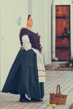 Portrait of brunette woman dressed in historical Baroque clothes with old fashion hairstyle, outdoors. Working class medieval dress