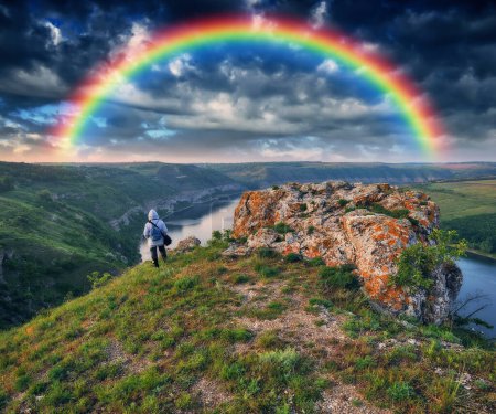 Touristen stehen am Rand der Klippe und blicken auf den Regenbogen. Regenbogen über dem Fluss. Natur der Ukraine