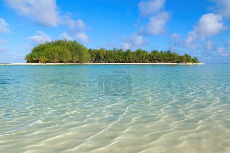 A tiny tropical island seen from the rippling waters of a lagoon. Koromiri Island in Muri Lagoon, Rarotonga, Cook Islands