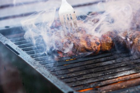 Photo for Preparing meat rolls called mici or mititei on barbecue. close up of grill with burning fire with flame and smoke. - Royalty Free Image