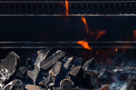 Téléchargez les photos : Barbecue grill fosse avec feu ouvert chaud et flamboyant avec flamme rouge, briquettes de charbon chaud et braises - en image libre de droit