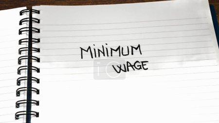 Foto de Texto escrito a mano del salario mínimo en papel, en la agenda de la oficina. Copiar espacio
. - Imagen libre de derechos