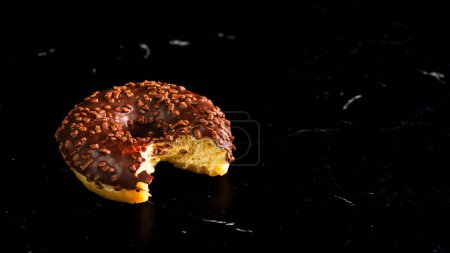 Fresh tasty colored donuts with sprinkles on black background