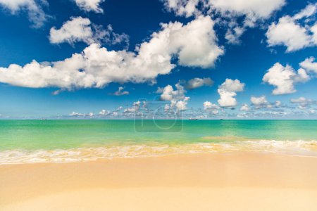 Karibischer Strand mit weißem Sand, tiefblauem Himmel und türkisfarbenem Wasser