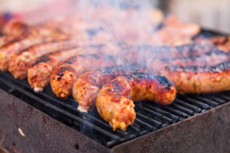 Griller les saucisses et les côtelettes de porc sur le barbecue. Barbecue dans le jardin