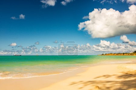Karibischer Strand mit weißem Sand, tiefblauem Himmel und türkisfarbenem Wasser