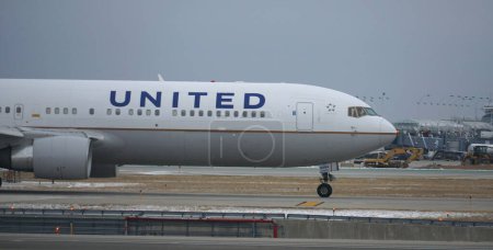 Téléchargez les photos : United Airlines plane taxies on the runway after landing at Chicago O'Hare International Airport on a winter day. - en image libre de droit