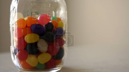Téléchargez les photos : Jelly beans in a glass jar against a white background - en image libre de droit