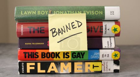 Téléchargez les photos : Une pile de livres trouvés sur des listes de livres fréquemment interdites avec une note collante disant "interdit". - en image libre de droit
