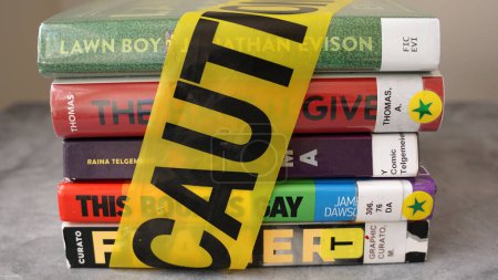 Téléchargez les photos : Une pile de livres trouvés sur des listes de livres fréquemment interdites emballés dans un ruban adhésif. - en image libre de droit