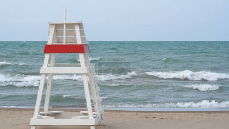 Empty lifeguard chair facing choppy waters on Lake Michigan when the water at Gillson Beach is closed due to high winds and riptides.                              