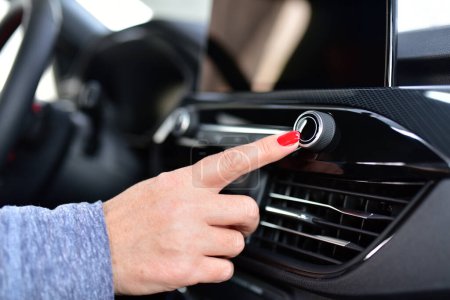 Das Autoradio einschalten. Der Finger einer Frau auf dem Knopf, um das Autoradio einzuschalten. 