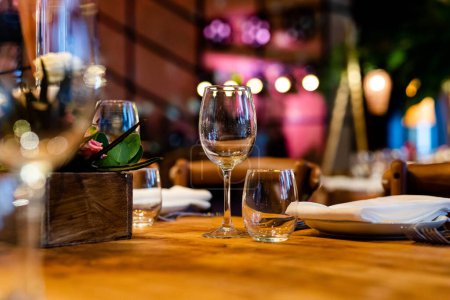 Luxuriöse Tischdekorationen für gehobene Küche mit und im Glas, Wein in Glas gießend. Schöne verschwommene Hintergrund. Vorbereitungen für die Hochzeit im Urlaub. Schickes Luxusrestaurant.
