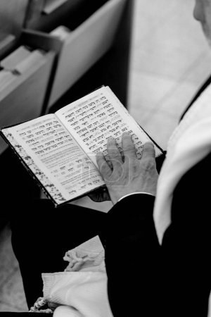 Photo for Jewish man praying in the synagogue tample of israel practicing the reading of the Torah prior to Bar Mitzvah celebration. wearing Tefillin on the right hand. - Royalty Free Image