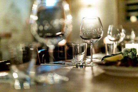 Téléchargez les photos : Verser du vin rouge dans un restaurant de luxe et des tabels luxueux. lumière élégante et plats. - en image libre de droit