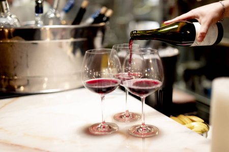 Téléchargez les photos : Verser du vin rouge dans un restaurant de luxe et des tabels luxueux. lumière élégante et plats. - en image libre de droit