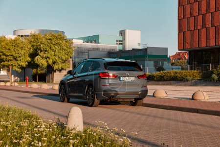 Téléchargez les photos : BMW X1 25e, hybride, voiture rechargeable, garée à côté d'un immeuble de bureaux moderne. La puissance totale des deux moteurs est de 220HP. Portée électrique jusqu'à 52 km Katowice, Pologne- 07.30.2021 - en image libre de droit