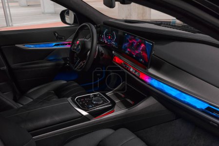 Foto de Interior y salpicadero de una serie BMW 7 con retroiluminación en modo deportivo, vista a través de la puerta abierta del pasajero. BMW Serie 7, G70, una limusina premium moderna. A la venta desde 2023. Polonia, Katowice 03.05.2023 - Imagen libre de derechos