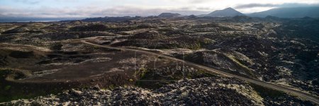 A view of the dirt road stretching to the horizon among the lava fields. Top view, photo taken from the drone. Helgafellssveit, Iceland.