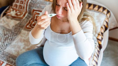 Photo for Pregnant thermometer temperature check. Pregnancy woman holding thermometer, check fever flu temperature. Pregnant girl sick. Concept of pregnancy, maternity, expectation for baby birth - Royalty Free Image