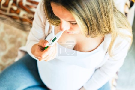 Photo for Pregnant temperature fever check. Pregnancy woman holding thermometer, check fever flu temperature. Pregnant girl sick. Concept of pregnancy, maternity, expectation for baby birth - Royalty Free Image