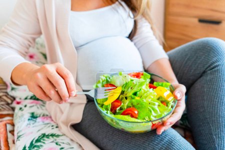 Foto de Pregnant salad healthy food. Pregnancy woman eating nutrition diet food salad. Family nutrition, healthy eating concept - Imagen libre de derechos
