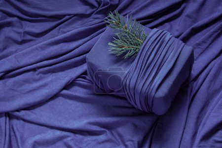 Photo for Trendy zero waste gift wrapping. Sustainable design concept. Christmas present in fabric on purple background with folds of fabric - Royalty Free Image