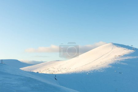 Photo for Skiing and snowboarding. A ski slope with a ski lift and small unrecognizable figures of people on a background of white snow, freeride - Royalty Free Image