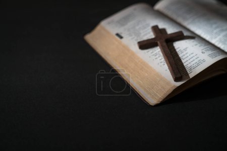 Wooden crucifix cross on top of an open Holy Bible. Selected focus, copy space.