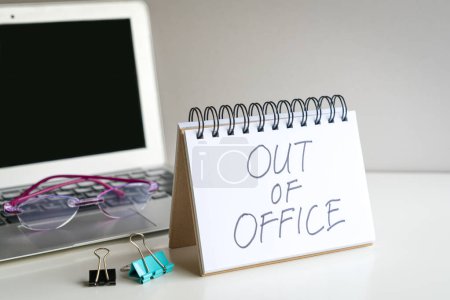 Fuera de la oficina, mensaje al lado de la computadora portátil. En el escritorio de oficina.
