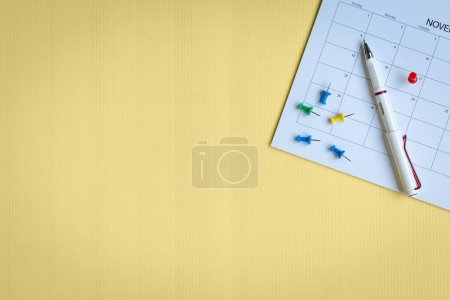 Foto de Calendario con alfileres de colores y bolígrafo, vista superior. Copiar espacio. - Imagen libre de derechos