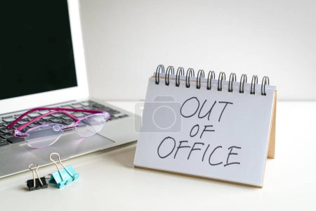 Hors du bureau, message à côté de l'ordinateur portable. Sur le bureau.