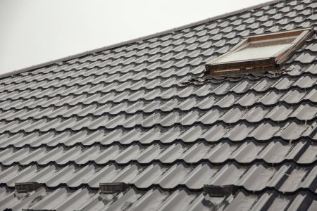 Metal tile roof with skylight window during heavy rain closeup