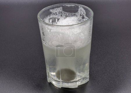 Téléchargez les photos : Comprimés effervescents instantanés dissolvants dans un verre d'eau en gros plan sur noir - en image libre de droit