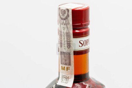 Photo for Kyiv, Ukraine - October 05, 2023: Closeup studio shot of excise stamp on the Soplica brand vodka bottle neck with plum flavor against white background. - Royalty Free Image