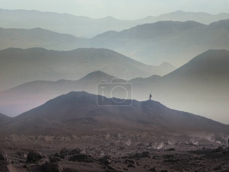 Foto de Espectacular cordillera en capas con niebla del valle. Hombre silueta llegar a cumbre disfrutando de la libertad
. - Imagen libre de derechos