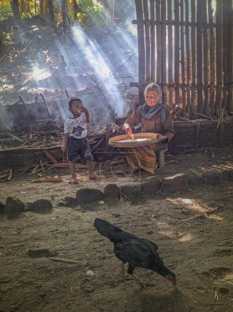 Foto de Yogyakarta, Indonesia. 25 de mayo de 2022. retrato de la abuela con su nieta en el bosque de bambú. La abuela javanesa estaba limpiando arroz antes de cocinar. - Imagen libre de derechos