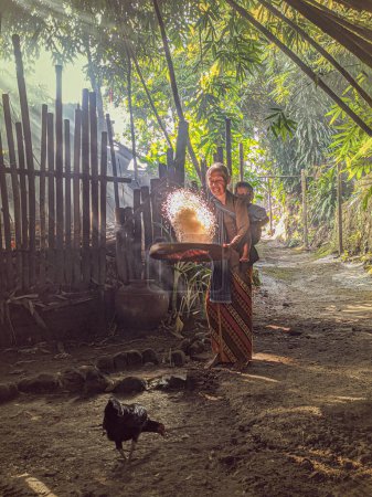 Foto de Yogyakarta, Indonesia. 25 de mayo de 2022. retrato de la abuela con su nieta en el bosque de bambú. La abuela javanesa estaba limpiando arroz antes de cocinar. - Imagen libre de derechos