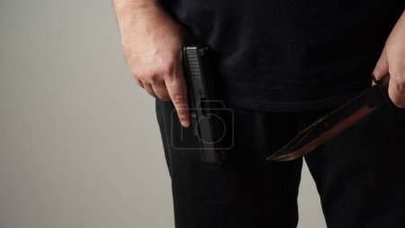 Téléchargez les photos : Male hands holding combat black Knife and a gun - en image libre de droit