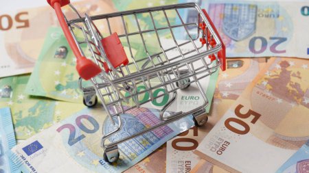Einkaufswagen über Geld Hintergrund. Bunte Euro-Banknoten