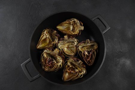 Photo for Oven roasted artichokes with garlic, rosemary and sauce on table - Royalty Free Image