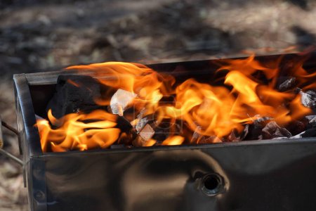 Téléchargez les photos : Empty Barbecue Flaming Grill Close Up With Bright Flames And White firelighters burning - en image libre de droit